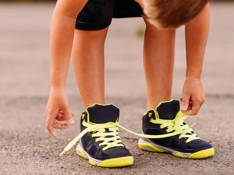 Chlapec si zavazuje sportovní tenisky Befado na hřišti